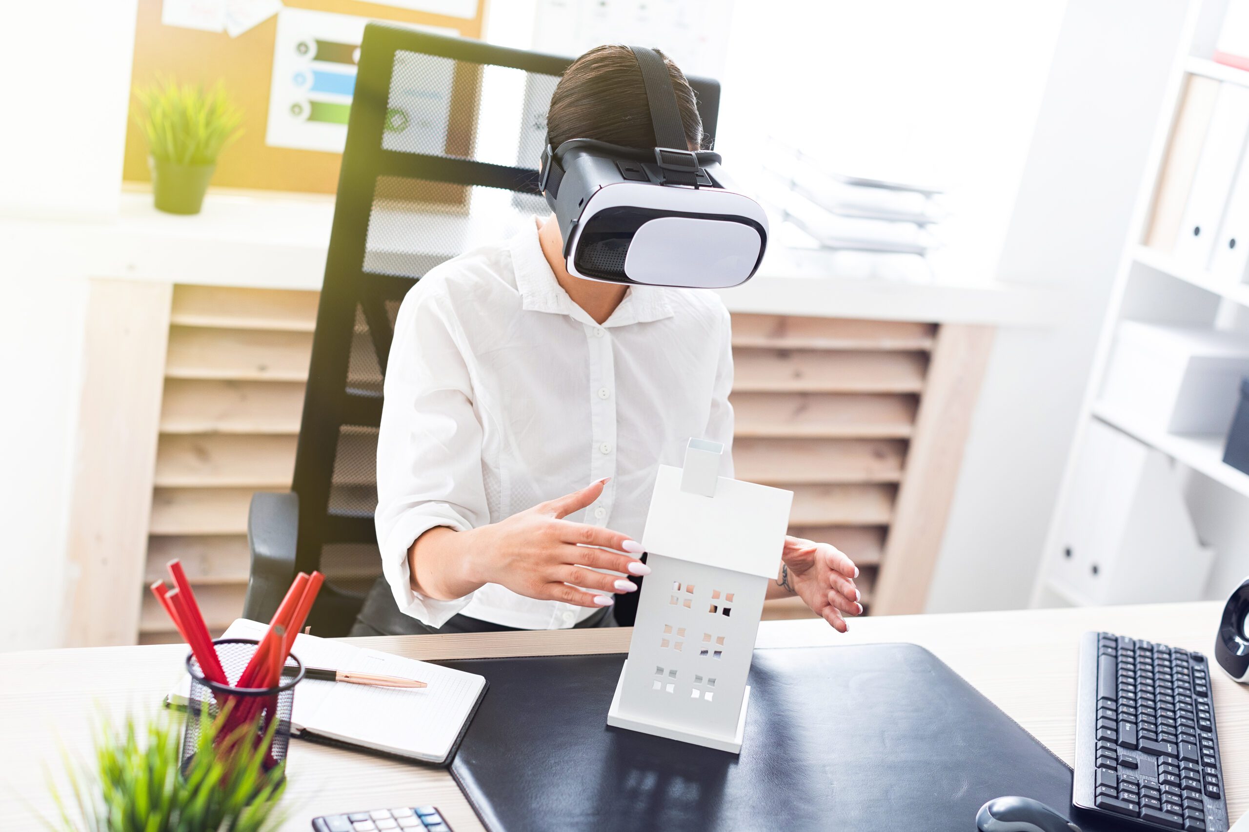 Young girl sitting in virtual reality glasses. Before her on the table is the layout of the house.